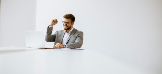 Young man working on laptop in bright office