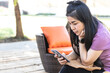 © lllonajalll - Asian beautiful woman is using smartphones. A happy woman holding a mobile phone sitting on a comfortable sofa in the garden.