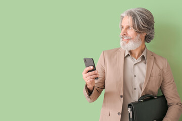 Wall Mural - Portrait of senior businessman with mobile phone on color background