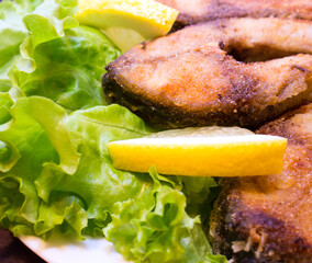  Baked steak carp with lemon on lettuce. A traditional fish recipe. Close-up.