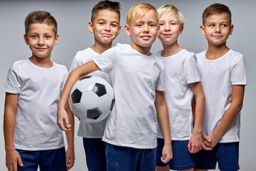 Wall Mural - kids soccer players celebrate a winning in school sports tournament, studio portrait of happy joyful kids in uniform engaged in football