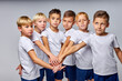 © Roman - friendly children soccer team getting ready to play, holding hands together, hoping to win, in uniform, isolated in studio