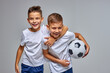 © Roman - kid boys go in for soccer sport professionally, stand hugging each other, have fun, smile at camera, holding ball in hands, isolated portrait