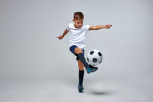 Young Caucasian Boy With Soccer Ball Doing Flying Kick Isolated In Studio, Athletic Sportive Boy In Uniform