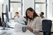 © Paul Bradbury/Caia Image - Businesswoman reviewing paperwork at desk in open plan office