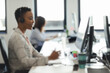 © Paul Bradbury/Caia Image - Businesswoman in headset working at computer in call center office