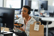 © Paul Bradbury/Caia Image - Portrait confident businesswoman eating takeout lunch at office desk