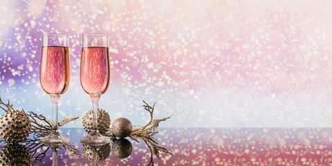 Two glasses of rose champagne and Christmas or New Year decoration with a golden light bokeh on background. Romantic dinner. Winter holiday concept.