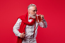 Man Raises A Glass To Everyone In Honor Of The Holiday, Senior Male Holding Glass Of Beer Isolated On Red Background
