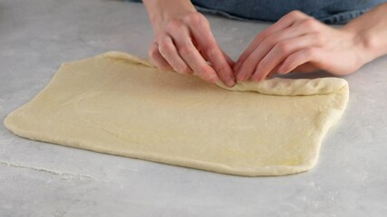 Wall Mural - Beautiful female hands in a professional kitchen roll the dough into a roll for making bread and buns. Yeast bread. Bread made from milk, butter, flour, eggs and yeast.