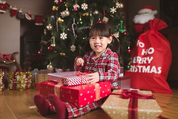 young girl sit on floor and open Christmas gift box at home