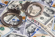 Handcuffs On Money Background. Dollar Bills, Money Cash Corruption, Dirty Money Financial Crime And Metal Police Handcuffs