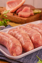 Sticker - Brazilian pork leg sausage on white plate with pork leg in background - Linguiça de pernil close up