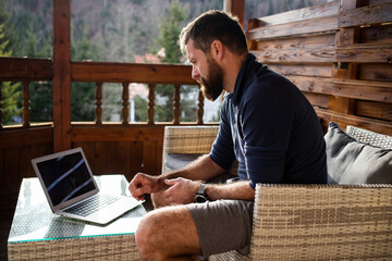 man working on laptop in wooden cottage