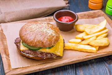 Wall Mural - Burger with meat and cheese on the board with french fries and tomato sause