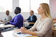 © JackF - Cheerful woman listening lecture with interest and taking notes during adult education class..