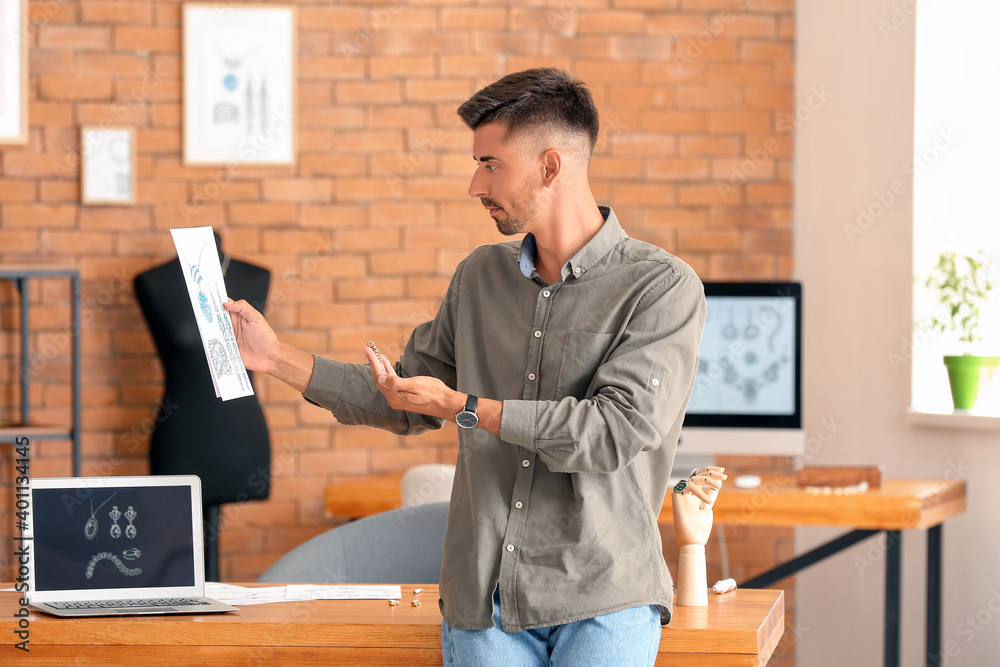 Male jewelry designer with sketches working in office