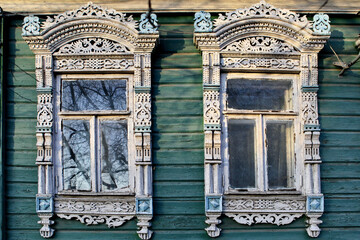 Richly decorated traditional national windows with carved frames on wooden rural house in Rostov Veliky town, Yaroslavl region, Russia. Russian folk style in architecture. Landmark, building facade