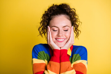 Wall Mural - Photo of lady arms touch cheekbones enjoy eyes closed wear rainbow pullover isolated yellow color background