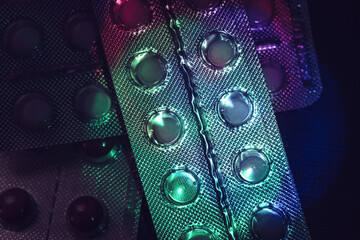 Poster - Pills or drugs in a package under neon light on a dark background pattern for design..