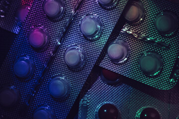 Poster - Pills or drugs in a package under neon light on a dark background pattern for design..
