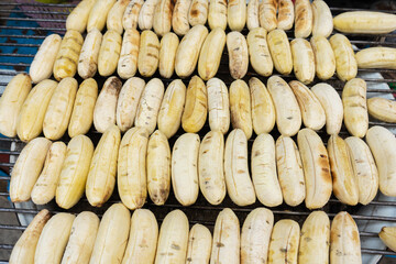 Wall Mural - street food in Thailand. The wire rack with peeled bananas is ready to cook. Fried bananas. Street food market