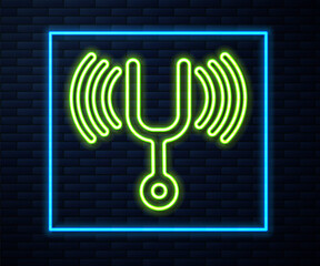 Sticker - Glowing neon line Musical tuning fork for tuning musical instruments icon isolated on brick wall background. Vector.