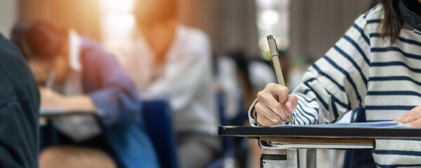 exam at school with student's taking educational admission test in class, thinking hard, writing ans
