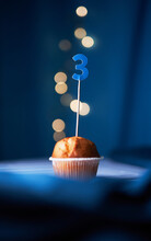 Birthday Cupcake Or Muffin With Number Three (3) And Lights On The Blue Background. Birthday Or Anniversary Concept