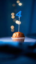 Birthday Cupcake Or Muffin With Number Four (4) And Lights On The Blue Background. Birthday Or Anniversary Concept