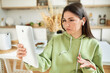 © Anatoliy Karlyuk - Serious student girl in comfy sweatshirt and wireless earphones learning distantly using portable touchscreen gadget, making grimace and helpless gesture, having problems with internet connection