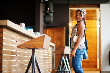 Wall Mural - Lovely african american woman with dreadlocks in leopard outfit at cafe. Beautiful cool fashionable black young girl indoor.