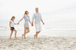 © momentimages/Tetra Images - Girl (10-11) walking on beach with parents