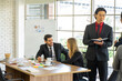 © ake - mixed race standing businessman and  colleague presented the project idea in the office  by teleconference online during social distancing work from home
