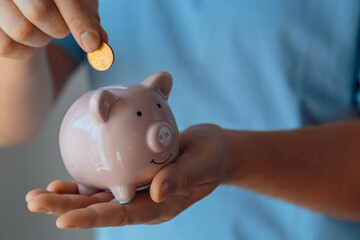 The man put the coin in the piggy bank. Money saving concept