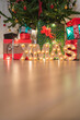 © Alvaro Sanchez/ADDICTIVE STOCK - Christmas tree with wrapped presents and wooden letters of word xmas with light bulbs in cozy room