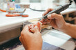 © Dani Navarro/ADDICTIVE STOCK - Unrecognizable male technician working in lab and using polishing machine for producing denture