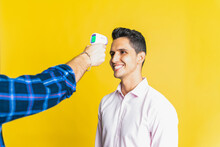 Crop Unrecognizable Male Measuring Temperature Of Happy Colleague Using Digital Thermometer On Yellow Background