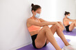 © Dani Navarro/ADDICTIVE STOCK - Exhausted female athlete in sports clothes and face protection mask sitting with closed eyes on mat near wall and mirror after exercising in gymnasium