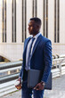 © David Espejo/ADDICTIVE STOCK - Full body side view of confident respectable African American businessman in formal outfit walking on street against contemporary buildings in modern downtown