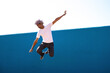 © David Munoz/ADDICTIVE STOCK - Black and afro man dressed in white jumping on a blue wall. Parkour concept.