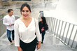 © Fatima Guisado/ADDICTIVE STOCK - From above of young glad female in stylish wear standing on staircase behind multiracial partners on street and looking at camera