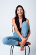 © Galdric Penarroja/ADDICTIVE STOCK - Full body delighted slim female model in tight jeans and top sitting on chair in light studio