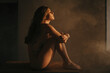 © Gustavo Pozo/ADDICTIVE STOCK - Side view of tranquil female in bodysuit sitting on wooden table and embracing knees while enjoying sunlight with closed eyes