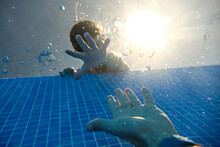 From Below View Of Faceless Boys Hand Reaching For Sinking In Swimming Pool Water Males Hand