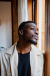 © Rafa Cortes/ADDICTIVE STOCK - Pensive young African American guy in casual clothes looking out window while resting at home in daylight