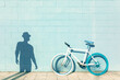 © Sergio Victor Vega/ADDICTIVE STOCK - Shadow of unrecognizable man on blue wall near stylish bicycle parked on sidewalk on sunny day