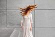 © Antonio Ovejero/ADDICTIVE STOCK - Female with long red hair fluttering in wind standing against gray concrete wall on street
