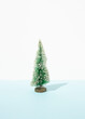 © Dani Enamorado/ADDICTIVE STOCK - Miniature of decorative Christmas tree placed on table in studio on blue background