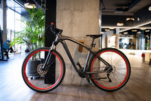 Modern Black Bicycle Parked Near Concrete Pillar Inside Contemporary Illuminated Gym During Workout
